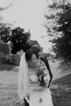 Candid black and white wedding photo of a couple laughing together outdoors.