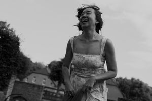 Candid black and white photo of wedding guests laughing and celebrating outdoors.