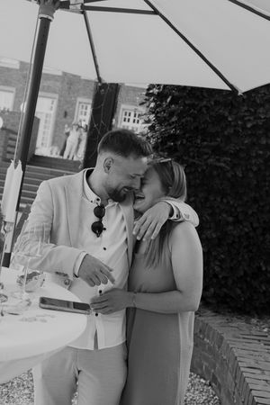 Intimate black and white photo of a couple sharing a tender moment at an outdoor reception.