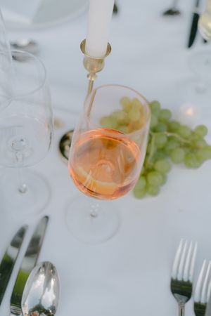 Glasses of rose wine and place settings on elegant white tablecloth.