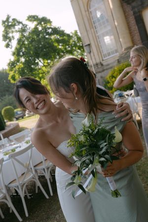Wedding party members sharing joyful moment with bouquets outdoors.