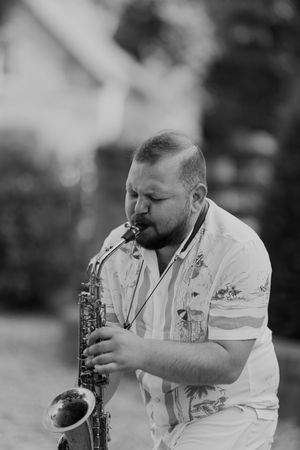 Musician playing saxophone during outdoor wedding performance.
