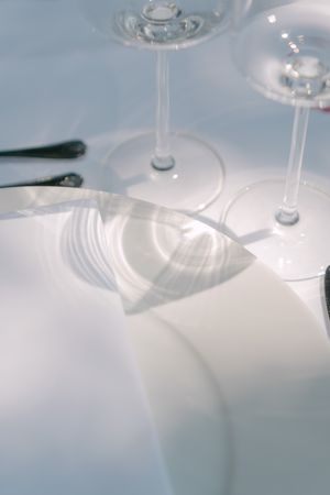 Abstract close-up of wine glasses creating soft reflections on a white surface.