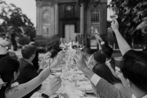 Wedding guests raise their glasses in a celebratory toast at an outdoor reception.