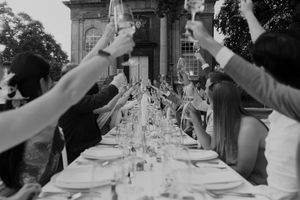 Wedding guests raise their glasses in unison during an outdoor celebration.