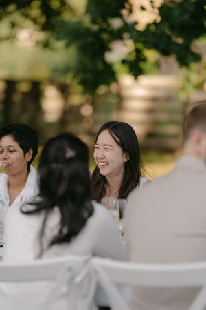 Guests in white attire share joyful moments at an outdoor wedding reception.