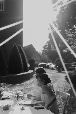 Black and white photo of wedding reception table with dramatic sunlight streaming through.