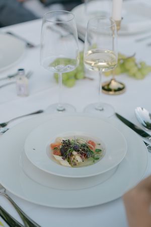 Elegant plated dishes with garnishes served at outdoor wedding reception.