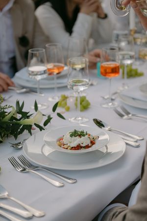 Formal place settings with white plates and elegant food presentation at wedding reception.