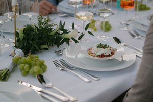 Elegant table setting with white plates, wine glasses, and fresh grapes at an upscale dining event.