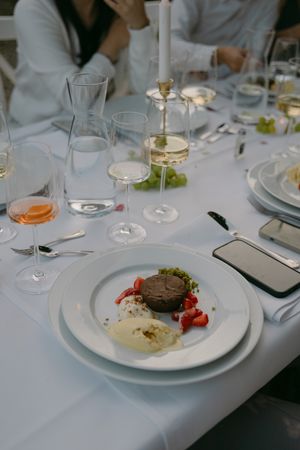 Fine dining place settings with white plates, wine glasses, and elegant table decorations.
