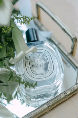 Crystal perfume bottle with embossed design reflected in a mirror surface.