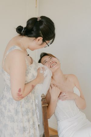 Candid moment showing joyful laughter in white lace dress.