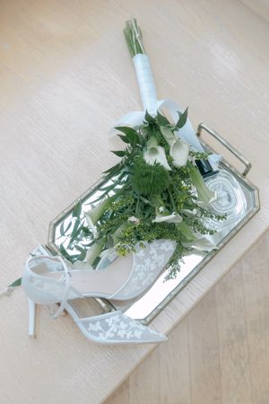 White floral arrangement displayed on a reflective mirrored tray with elegant styling.