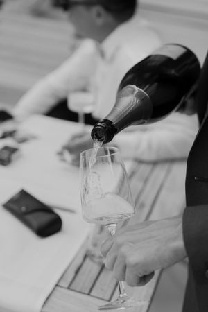 Champagne being poured into a glass at a formal event with a mobile phone visible on the table.