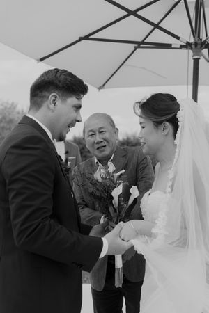 A joyful wedding ceremony moment under white umbrellas showing candid reactions and laughter.