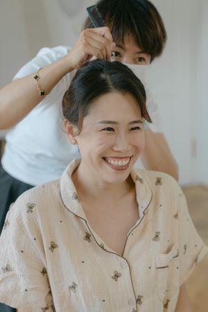 Person wearing a light patterned pajama top expressing joy in a bright room.