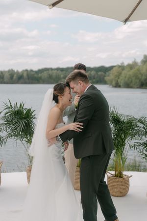 Emotional wedding ceremony moment against a serene lake backdrop.