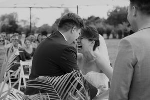 Black and white candid moment of couple laughing during outdoor wedding ceremony.
