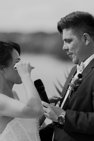 Black and white close-up of couple sharing emotional moment during vow exchange.