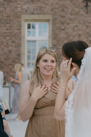 Wedding guests share an emotional moment outside a brick building during the celebration.
