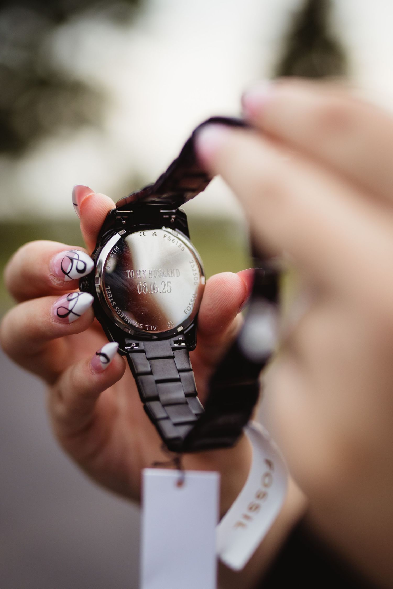 Close-up view of someone examining a black metal watch from different angles in sequence.