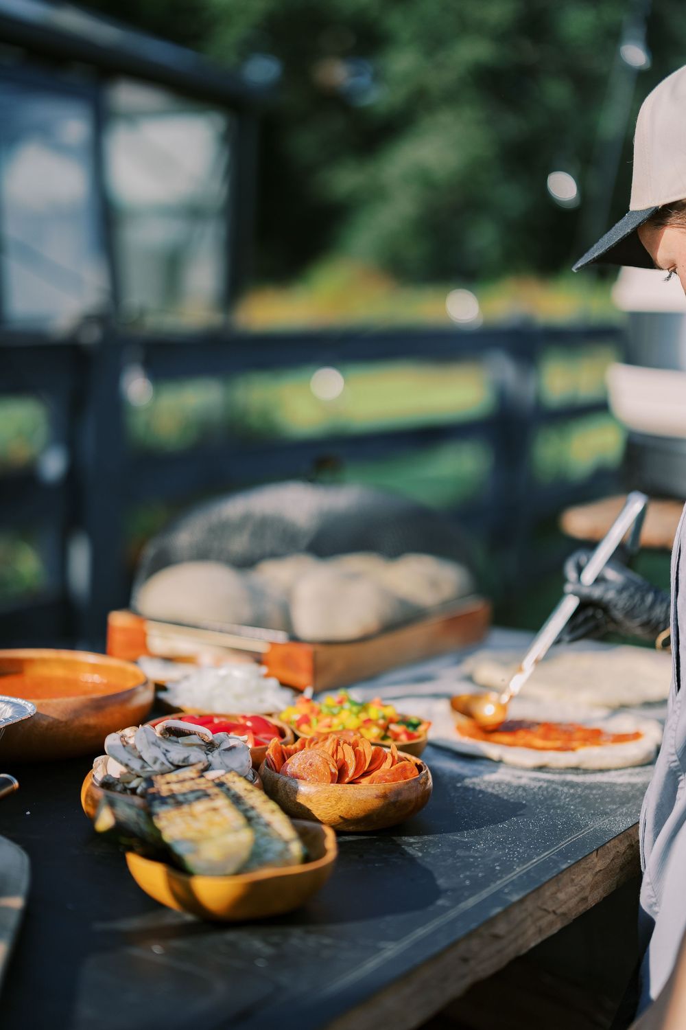 Grilled food dishes arranged on dark slate serving boards at an outdoor catering event.