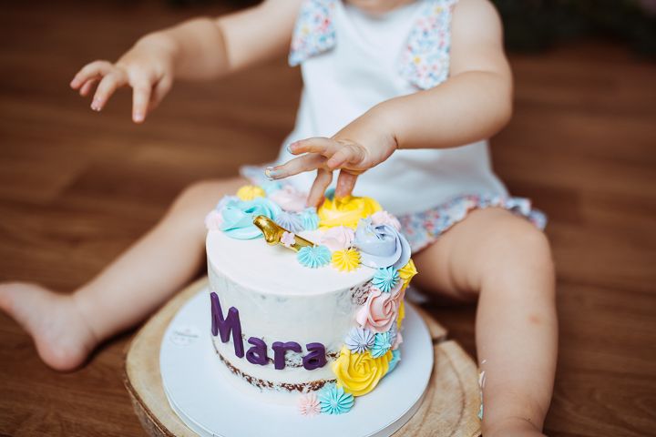 Close-up shots of a decorated birthday cake with colorful frosting and name plate on a rustic wooden surface.