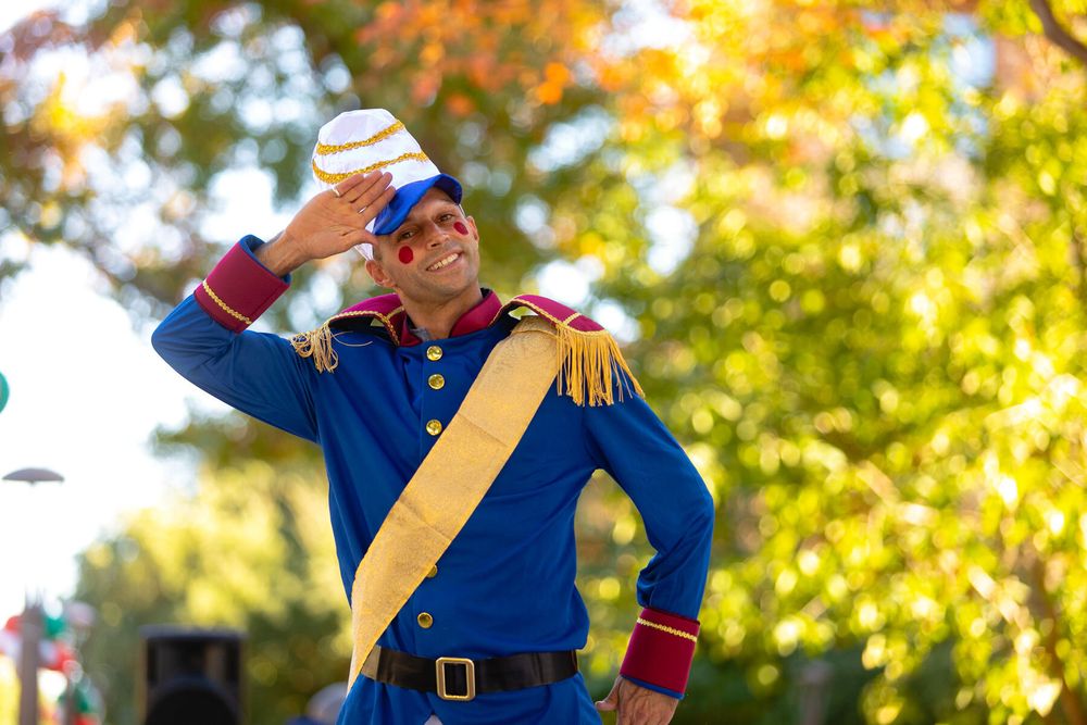 Historical reenactors in blue military uniforms perform demonstrations at an outdoor event on a sunny autumn day.