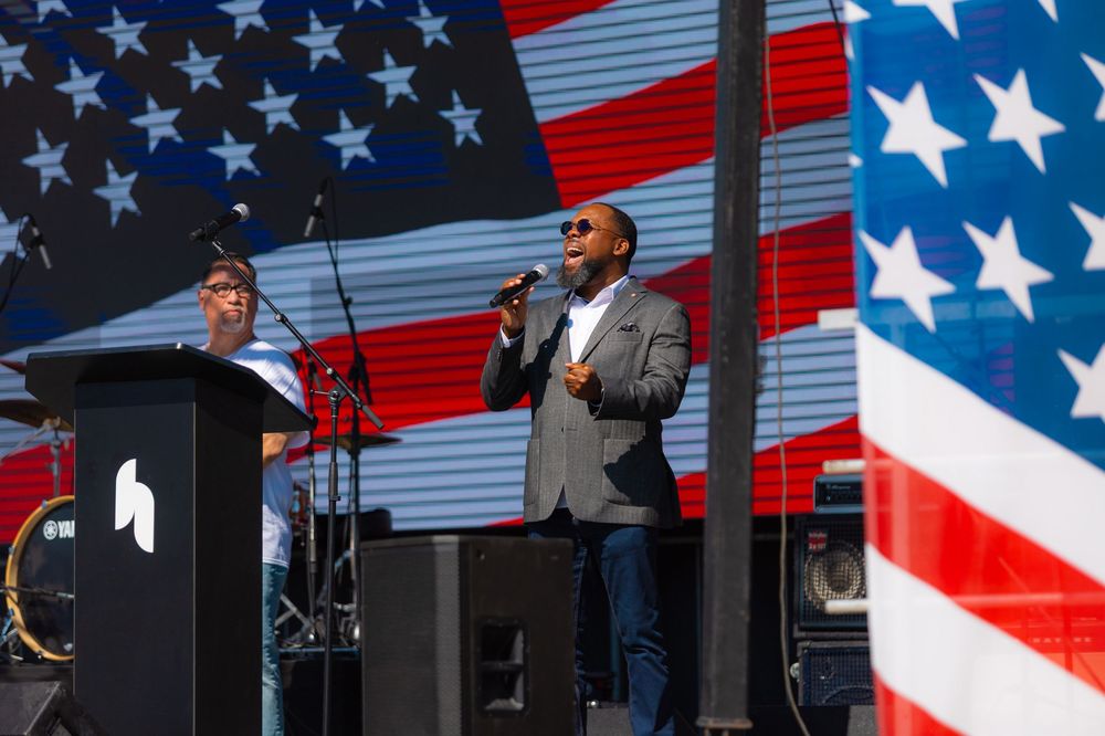 American flag backdrop displayed at an outdoor performance venue with stage lighting.