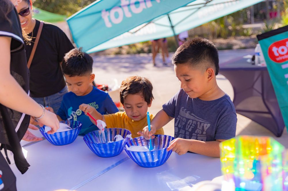 People sitting at tables playing with colorful plastic cups and game pieces at an outdoor event.
