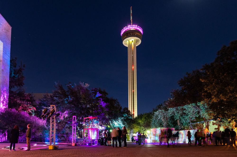 Night-time outdoor event space illuminated with colorful purple and blue lighting.