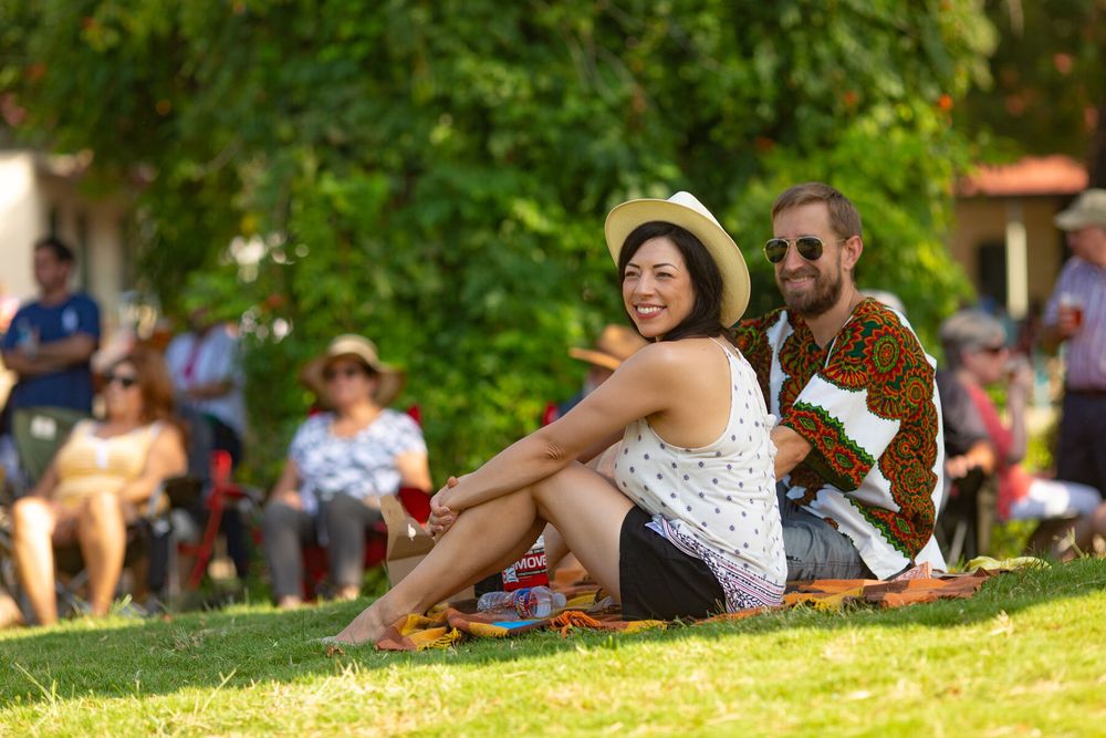 People relaxing on a grassy hillside during an outdoor summer event.