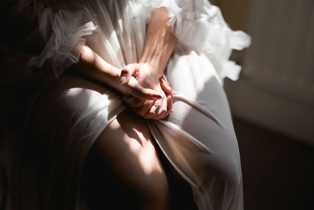 Delicate details of white wedding dress fabric captured in soft natural window light.