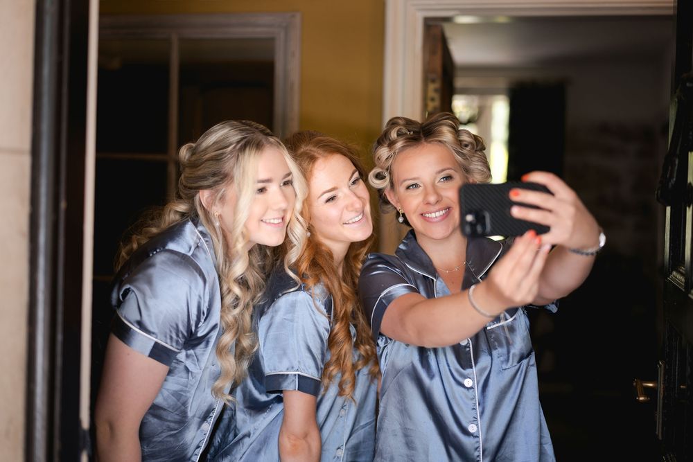 Bridesmaids wearing matching blue dresses pose together for a series of fun photos.