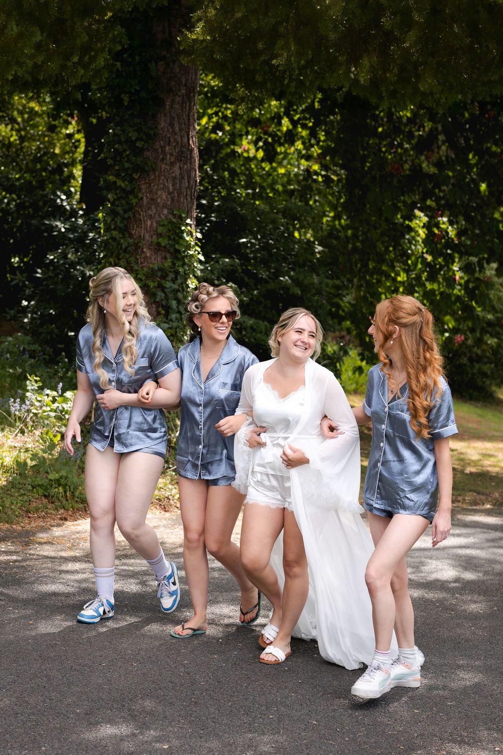 Wedding party wearing denim jackets poses casually on outdoor path.