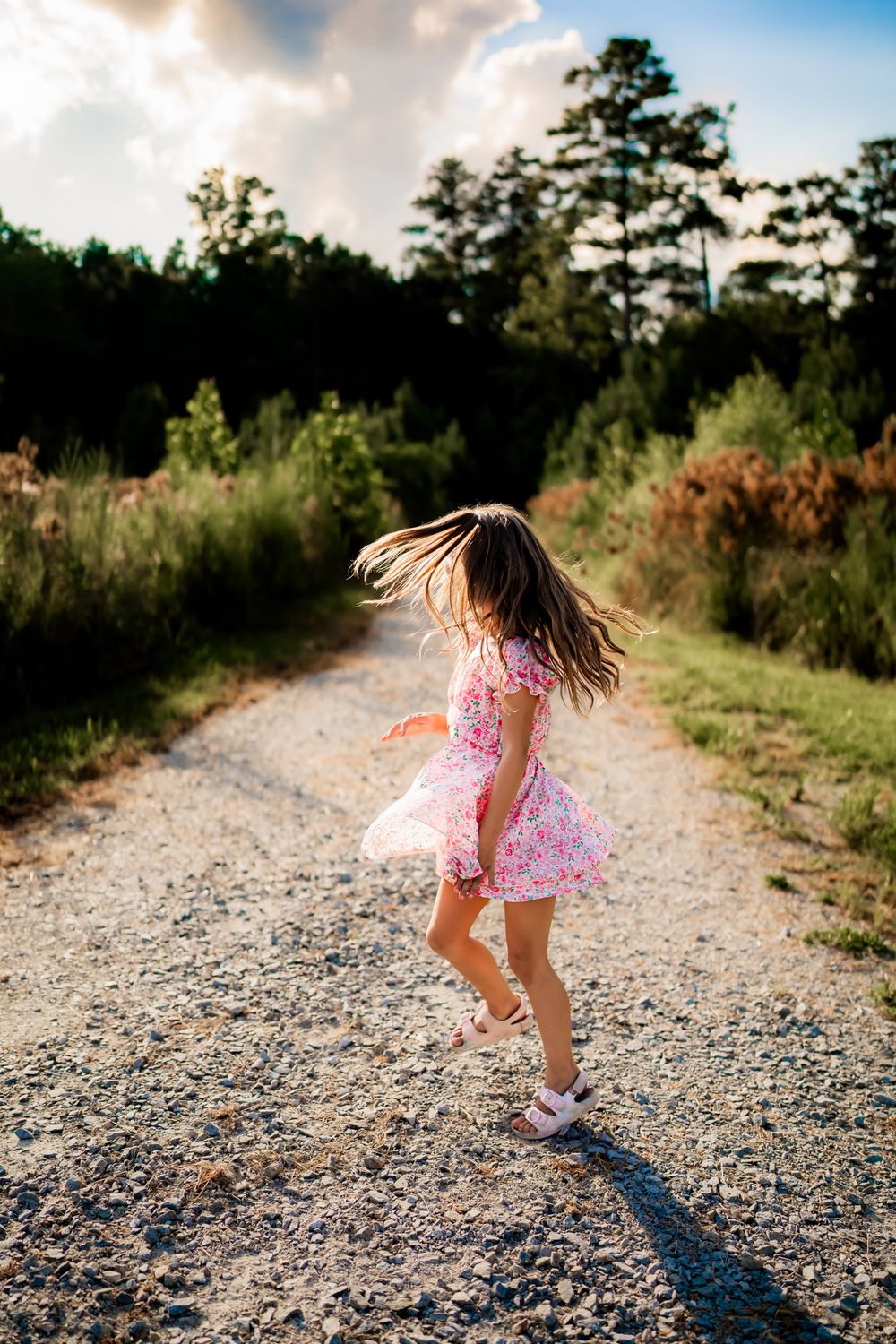 A series of action shots showing a child in pink clothing spinning and twirling on a gravel path at sunset.