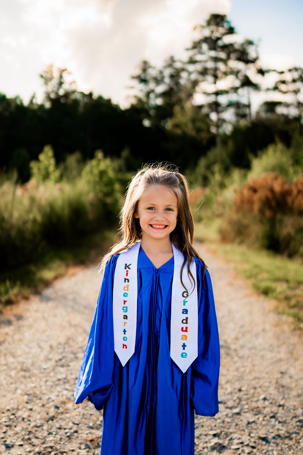 Progression series of graduate in bright blue gown and decorated stole walking on a sunlit gravel path.