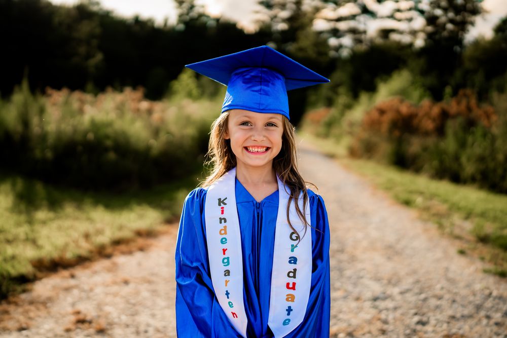 Graduation portrait series showing a graduate in blue cap and gown with decorated sash on a rural path at sunset.