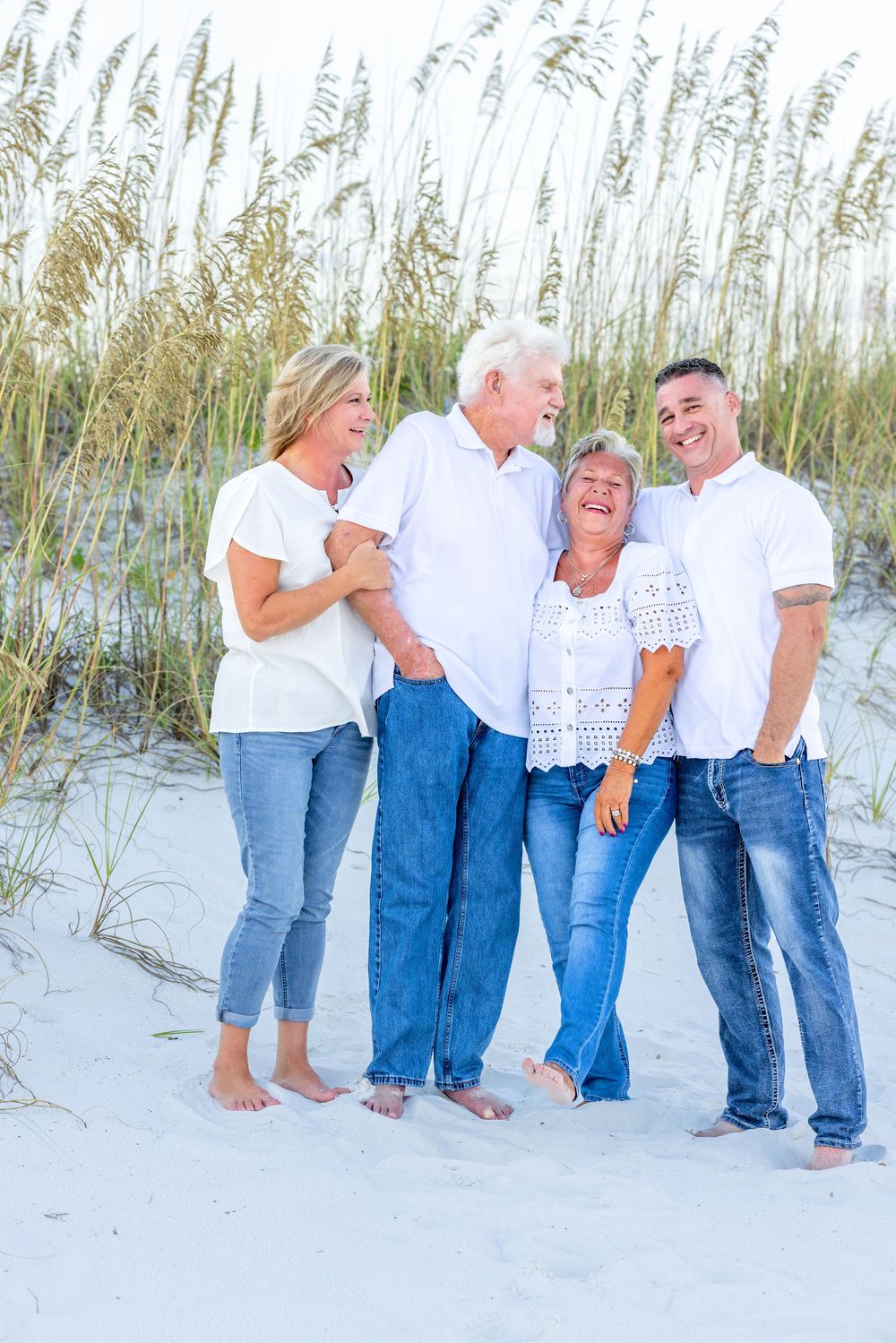 Group enjoying a casual gathering on a white sandy beach with sea oats in the background.