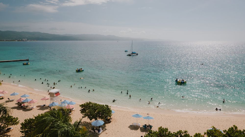Panoramic view of a tropical Hawaiian beach with sparkling turquoise water and boats anchored offshore.