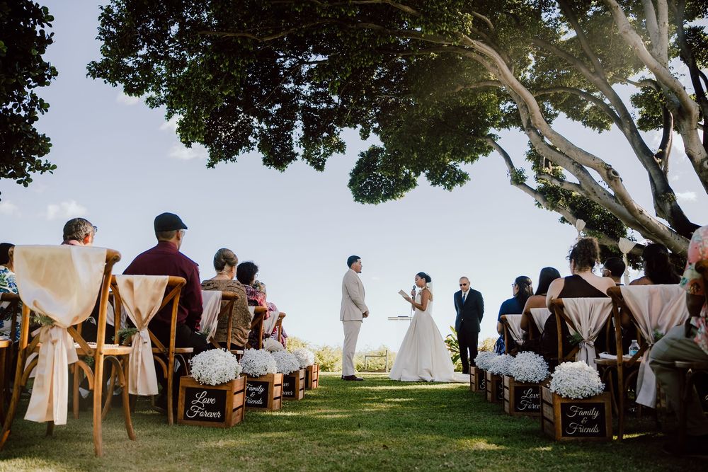 Outdoor wedding ceremony setup with white chairs arranged on a scenic overlook by the ocean.