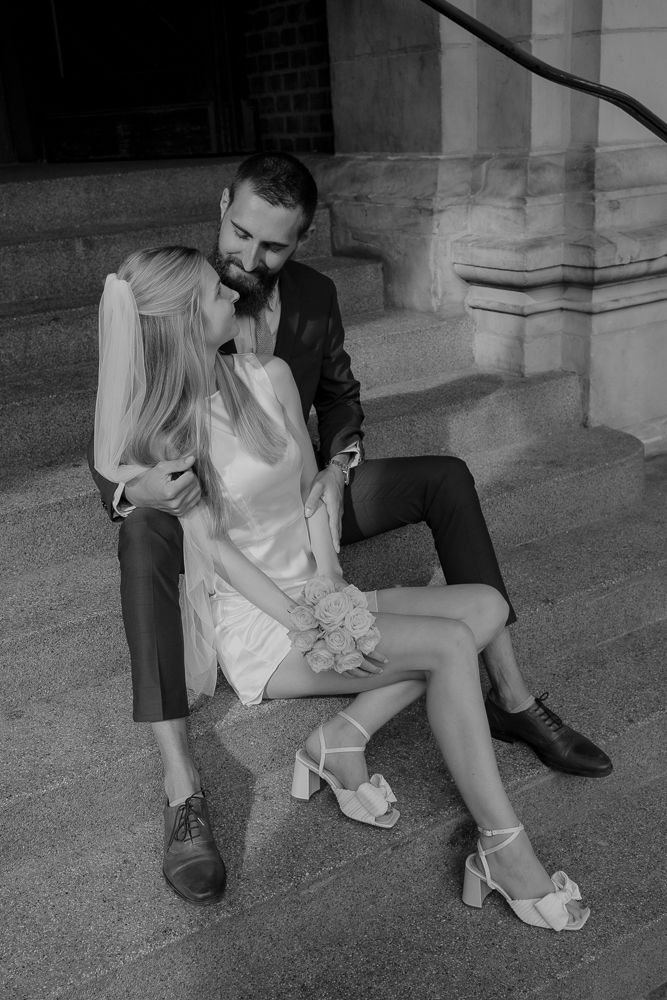 Schwarz-Weiß-Foto, das einen intimen Moment auf Steinstufen einfängt.