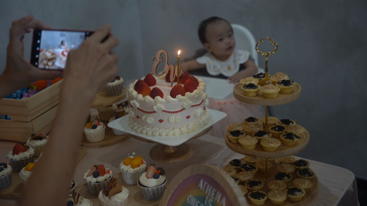 Birthday celebration setup with two-tier cake and cupcake tower display.