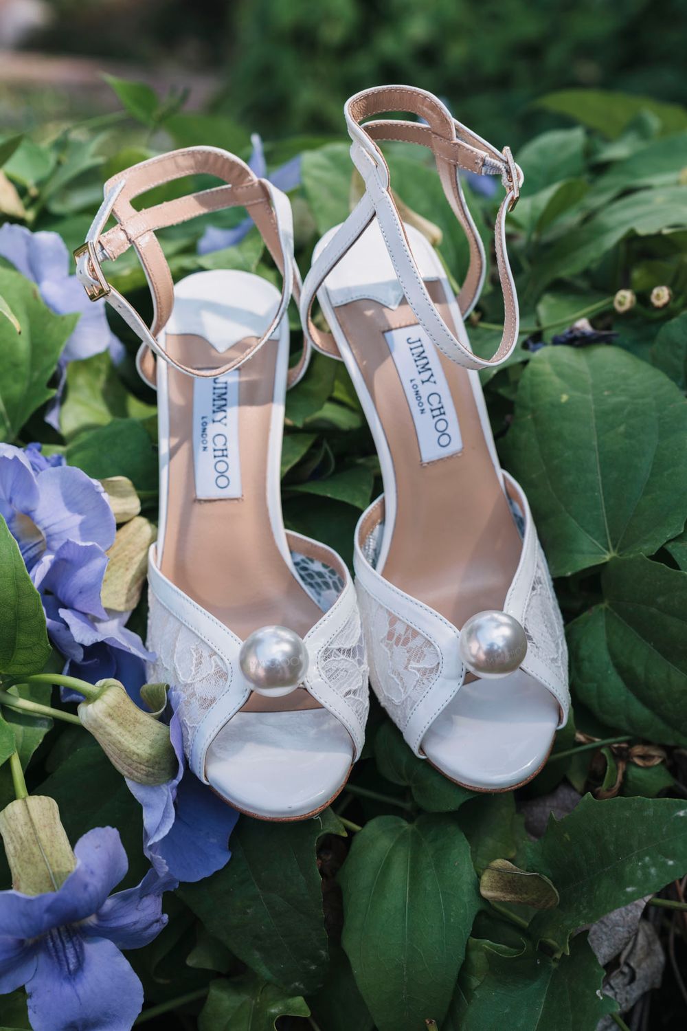Jimmy Choo bridal shoes with pearl details photographed among blue hydrangea flowers.