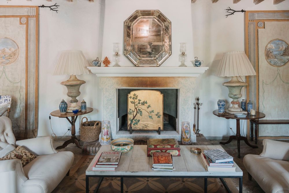 Elegant living room with octagonal mirror above fireplace, matching table lamps and comfortable seating.