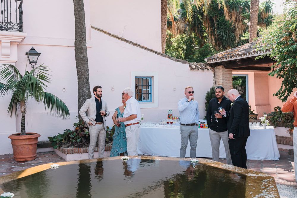 Wedding guests gathered around a water feature at an elegant outdoor reception.
