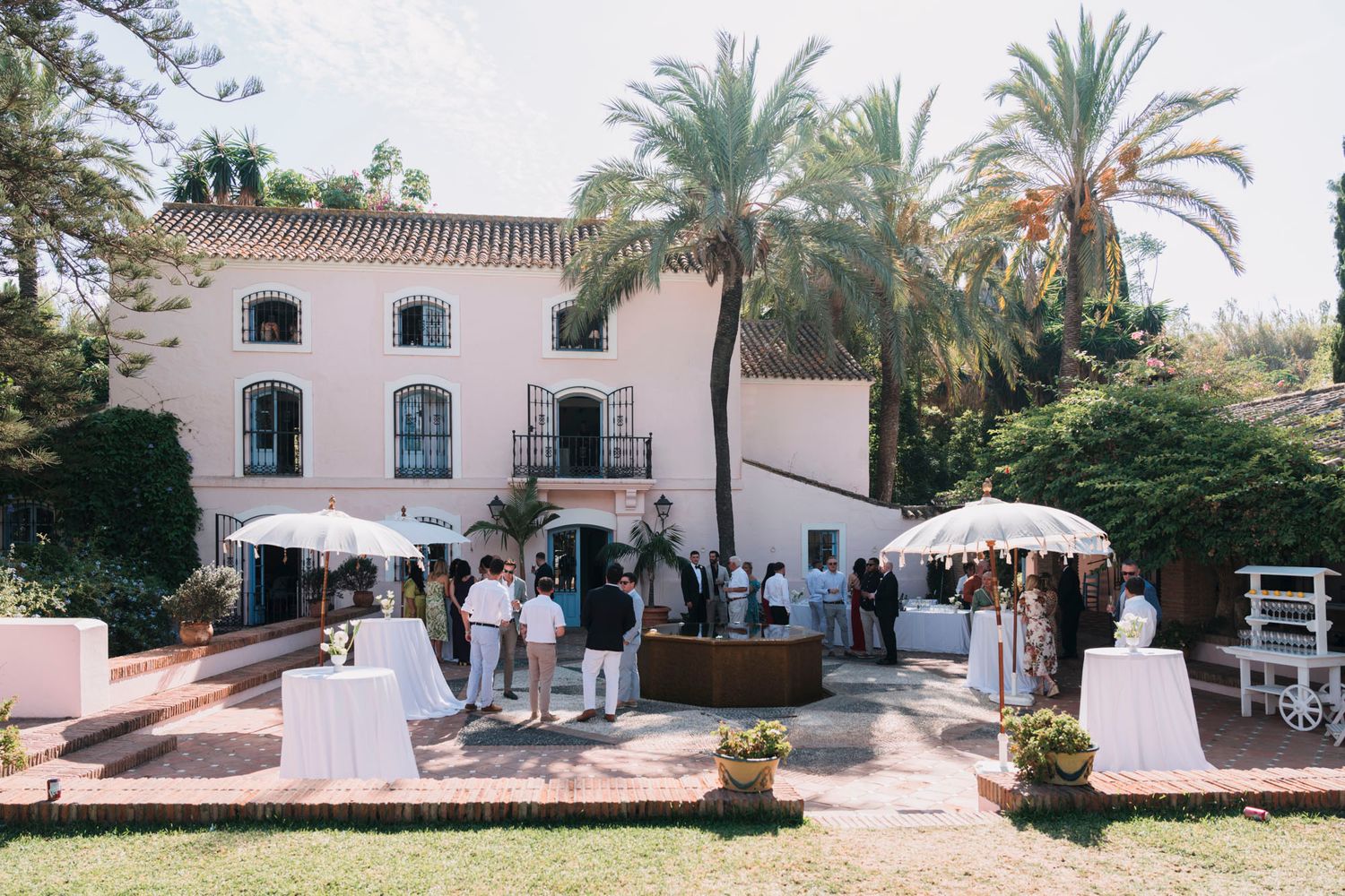 Mediterranean-style villa with palm trees hosting an outdoor wedding celebration.