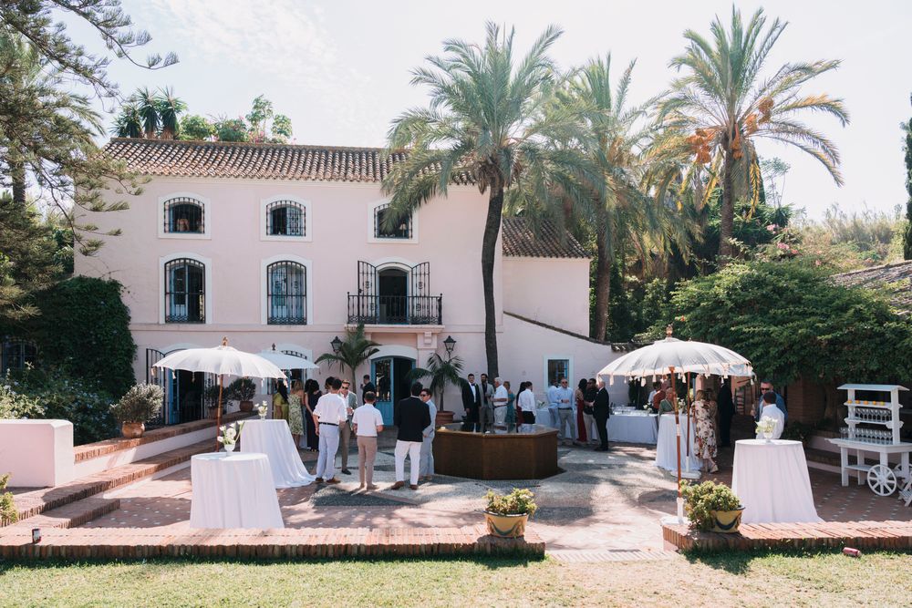 Mediterranean-style villa with palm trees hosting an outdoor wedding celebration.