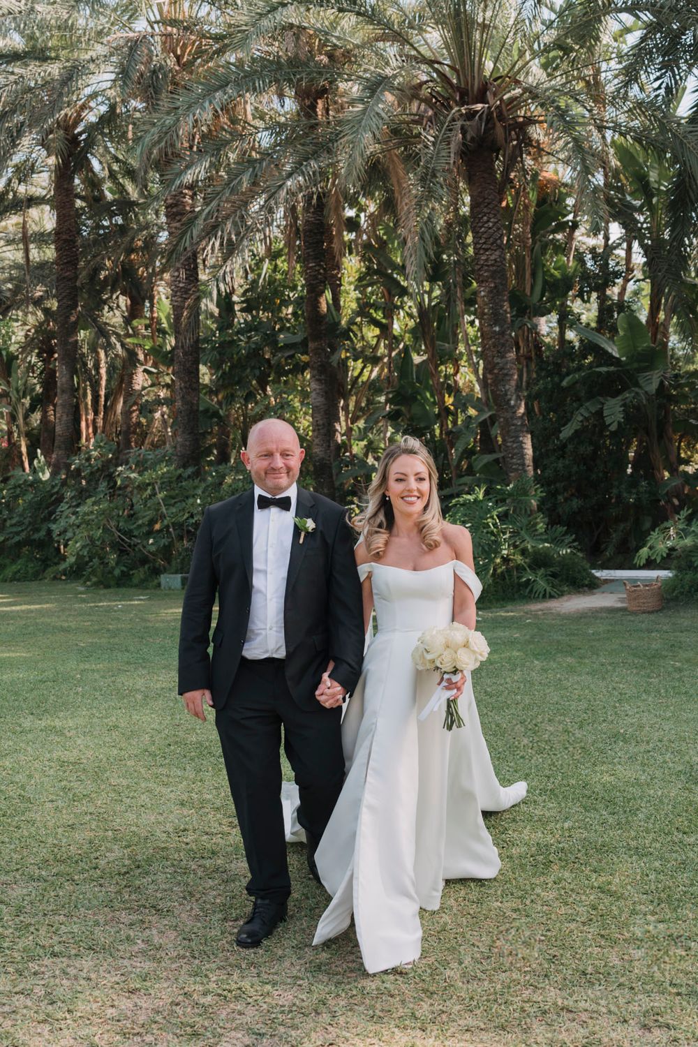 Couple walking through a picturesque palm garden during their wedding celebration.
